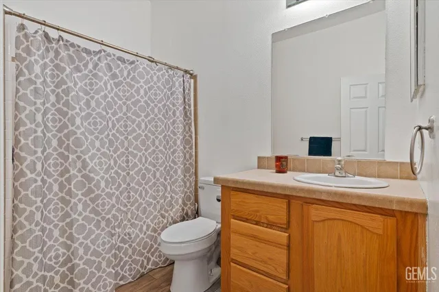 a bathroom with a granite countertop sink and a toilet