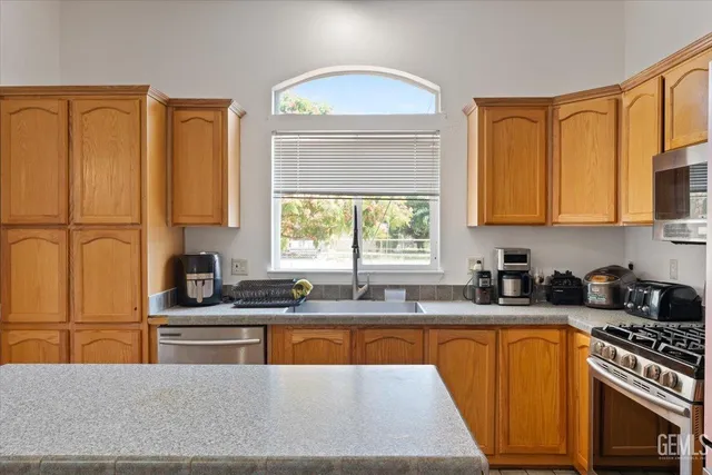 a kitchen with granite countertop a sink stainless steel appliances and cabinets