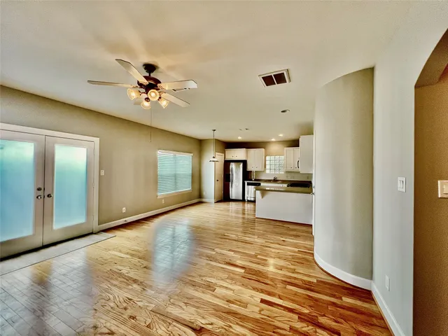a view of an empty room with kitchen view and a window