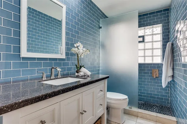 a bathroom with a granite countertop sink a toilet and shower
