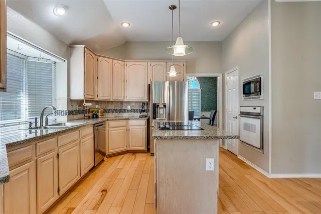 a kitchen with kitchen island granite countertop appliances cabinets and a sink
