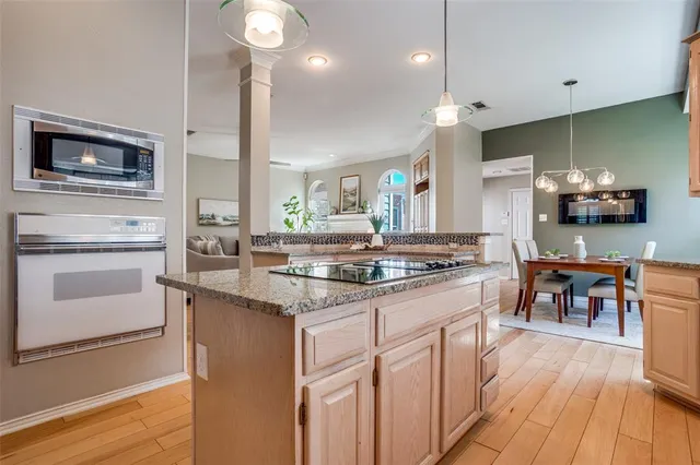 a kitchen with kitchen island granite countertop a stove a sink a dining table and chairs with wooden floor
