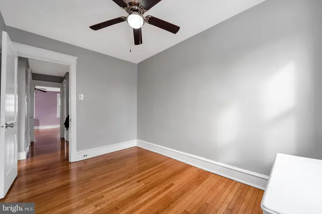 an empty room with wooden floor and a ceiling fan