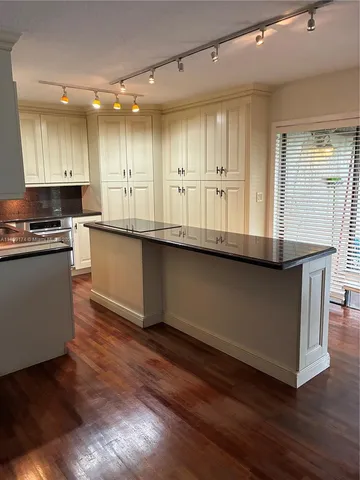 a kitchen with stainless steel appliances granite countertop a stove a sink and white cabinets