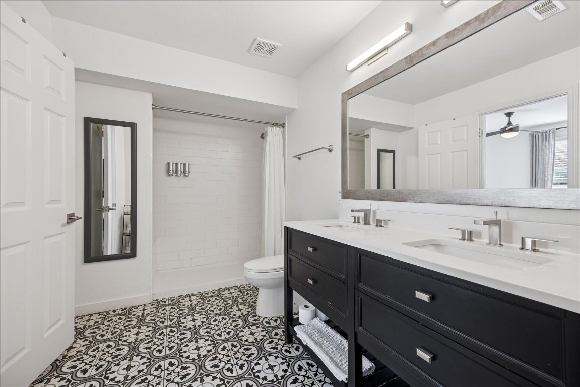 604 Pressler Street Austin, TX 78703 - Photo 11 of 40 Bathroom featuring a tile shower, double vanity, and dark tile patterned floors