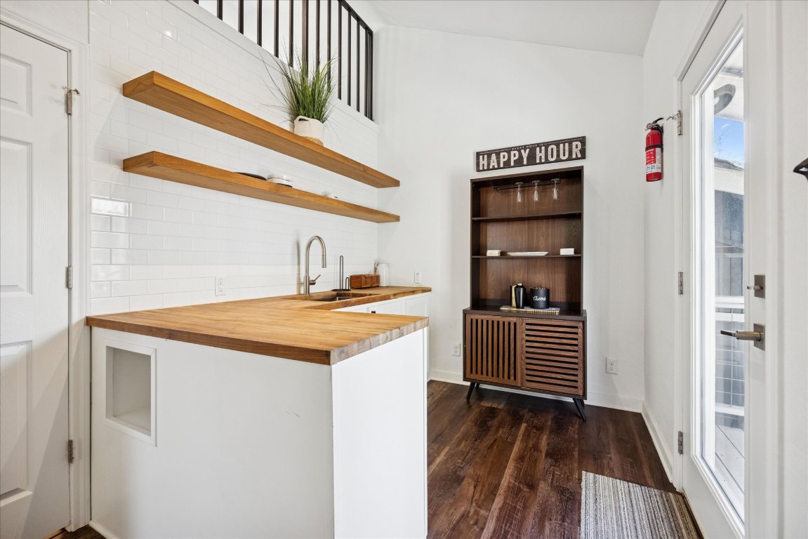 604 Pressler Street Austin, TX 78703 - Photo 17 of 40 Bar area featuring open shelves, butcher block countertops, dark wood-style flooring, white cabinetry, and lofted ceiling