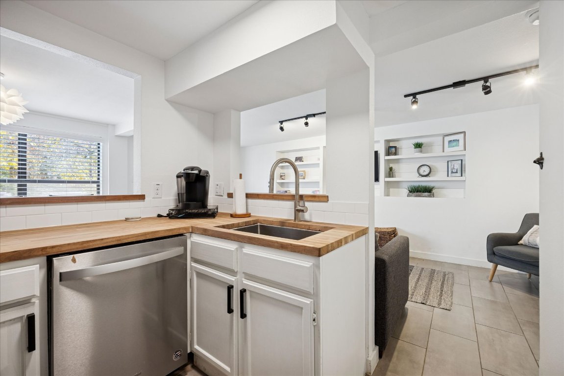 604 Pressler Street Austin, TX 78703 - Photo 29 of 40 Kitchen featuring white cabinetry, track lighting, stainless steel dishwasher, wooden counters, and light tile patterned floors
