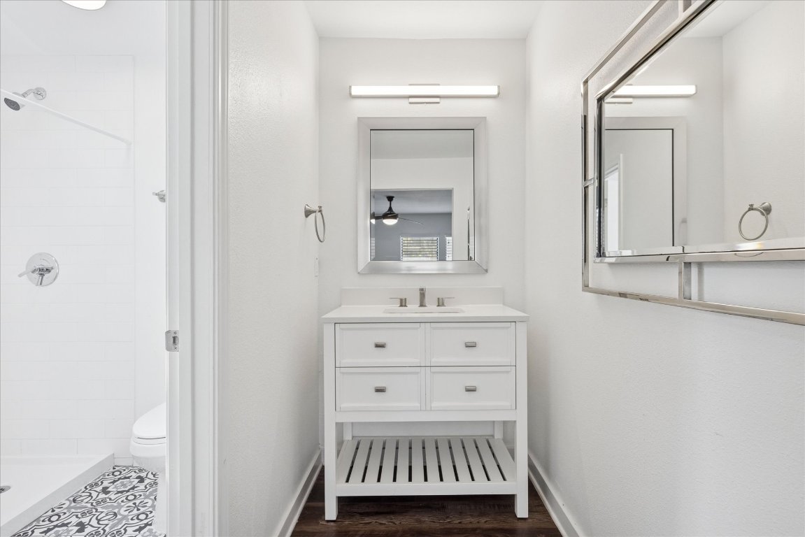 604 Pressler Street Austin, TX 78703 - Photo 36 of 40 Full bath featuring vanity, a tile shower, dark wood-style floors, and ceiling fan