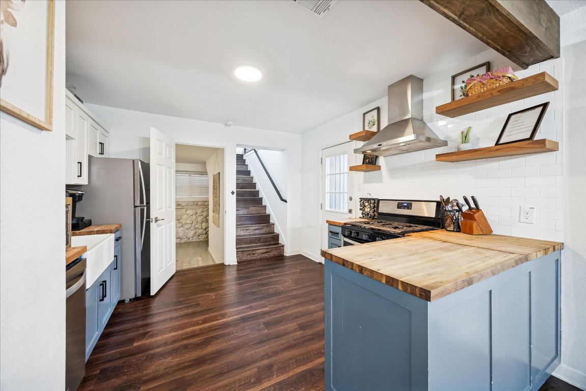 604 Pressler Street Austin, TX 78703 - Photo 6 of 40 Kitchen featuring butcher block countertops, tasteful backsplash, exhaust hood, and blue cabinets