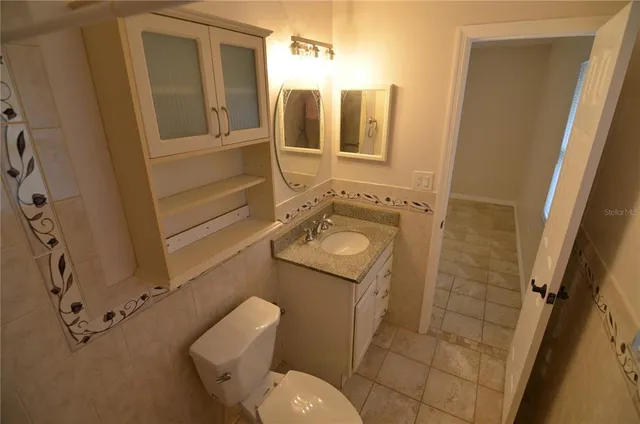 a bathroom with a granite countertop sink toilet mirror and bathtub