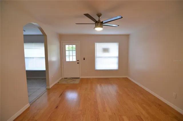 an empty room with wooden floor and windows