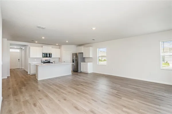 a view of kitchen with kitchen island wooden cabinets and refrigerator