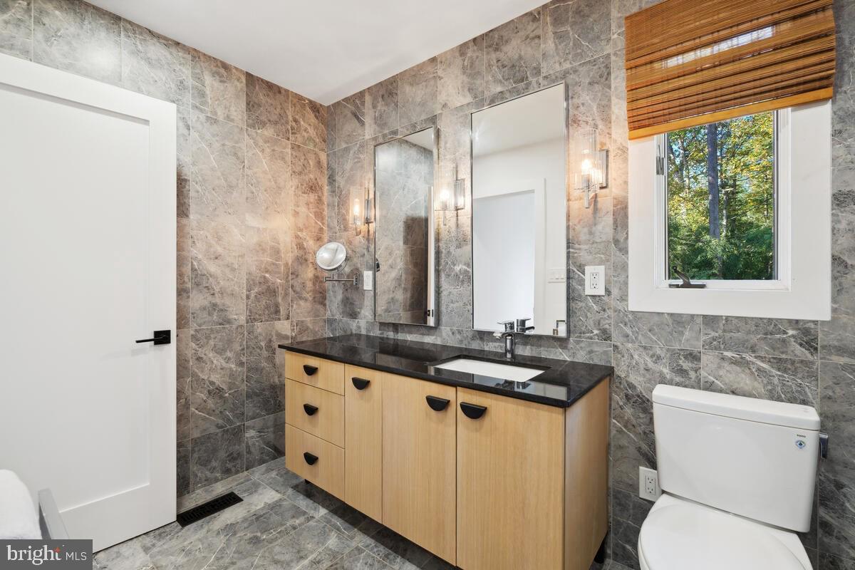 11900 Viewcrest Terrace Silver Spring, MD 20902 - Photo 47 of 69 a bathroom with a granite countertop sink a toilet a mirror and a window