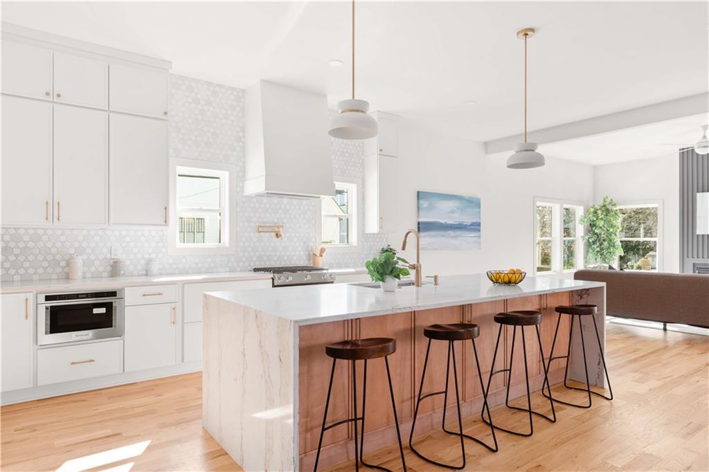286 Sisson Avenue Northeast Atlanta, GA 30317 - Photo 11 of 56 a kitchen with stainless steel appliances kitchen island granite countertop a dining table chairs and white cabinets