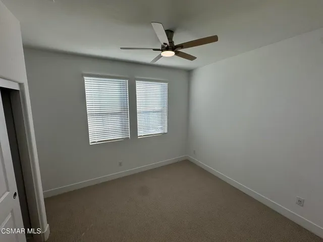 an empty room with a window and a fan