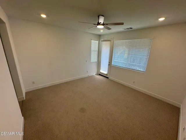 en empty room with windows and chandelier fan