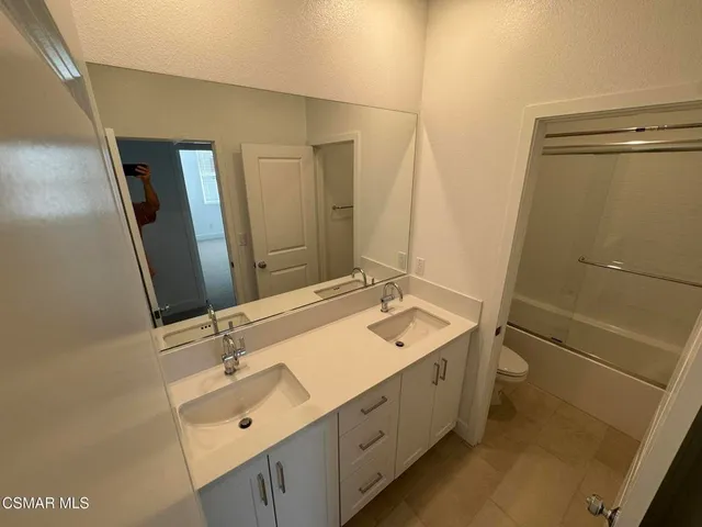 a bathroom with a double vanity sink toilet and mirror