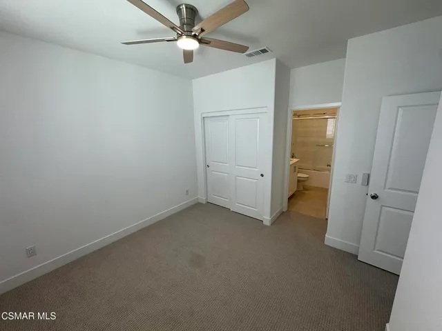 an empty room with closet and a ceiling fan