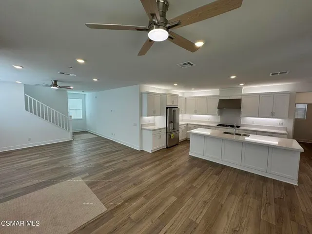 a large room with kitchen view and a chandelier fan