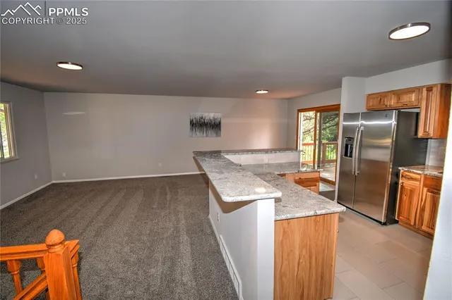 an empty room with wooden floor and a kitchen