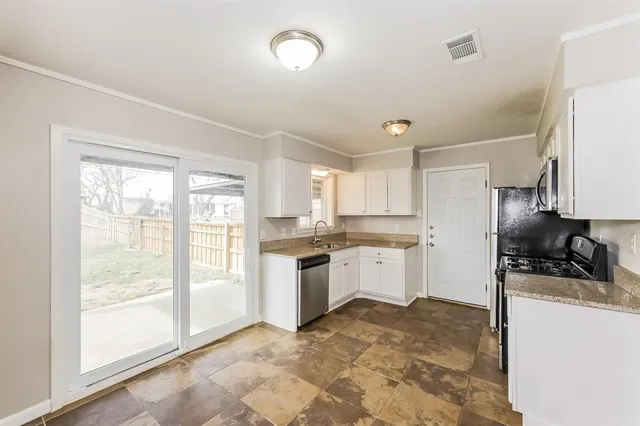 a kitchen with stainless steel appliances granite countertop a sink stove refrigerator and cabinets