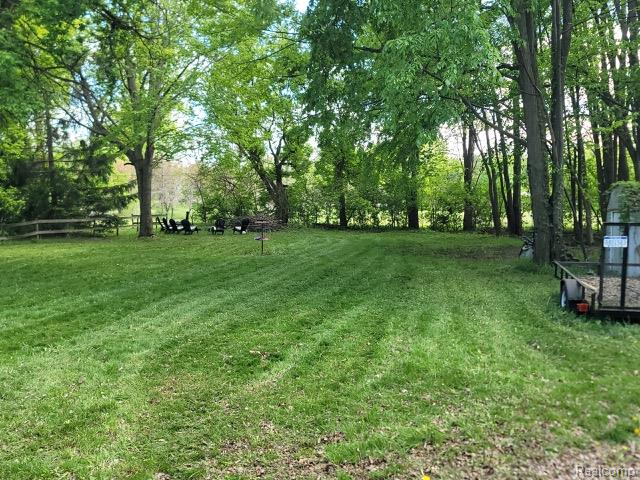 42263 Palmer Road Canton, MI 48188 - Photo 7 of 22 Expansive lawn area featuring mature trees, a split-rail fence, and a designated seating arrangement