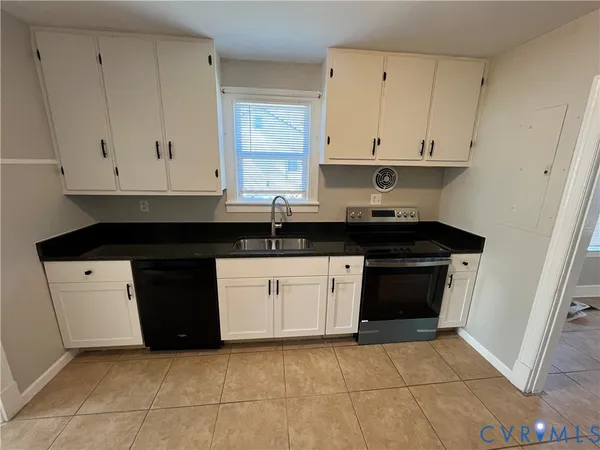 a large kitchen with a refrigerator a sink and white cabinets