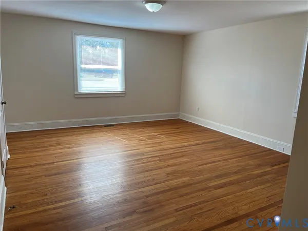 a view of an empty room with wooden floor and closet