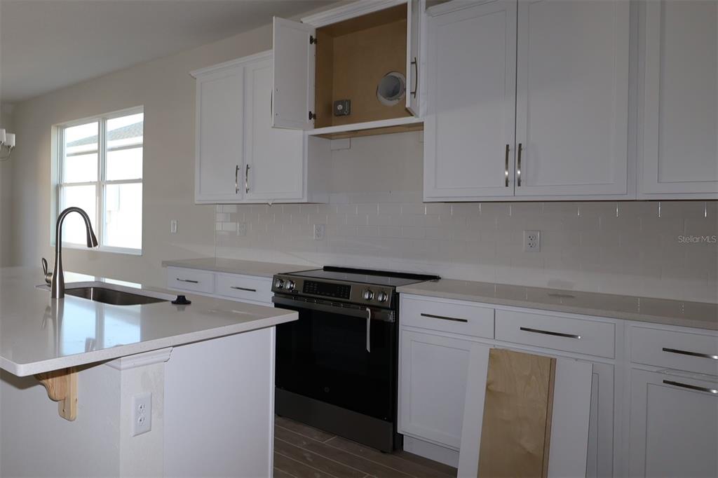 659 Pothos Street Apopka, FL 32703 - Photo 11 of 34 a kitchen with stainless steel appliances granite countertop a sink stove and cabinets