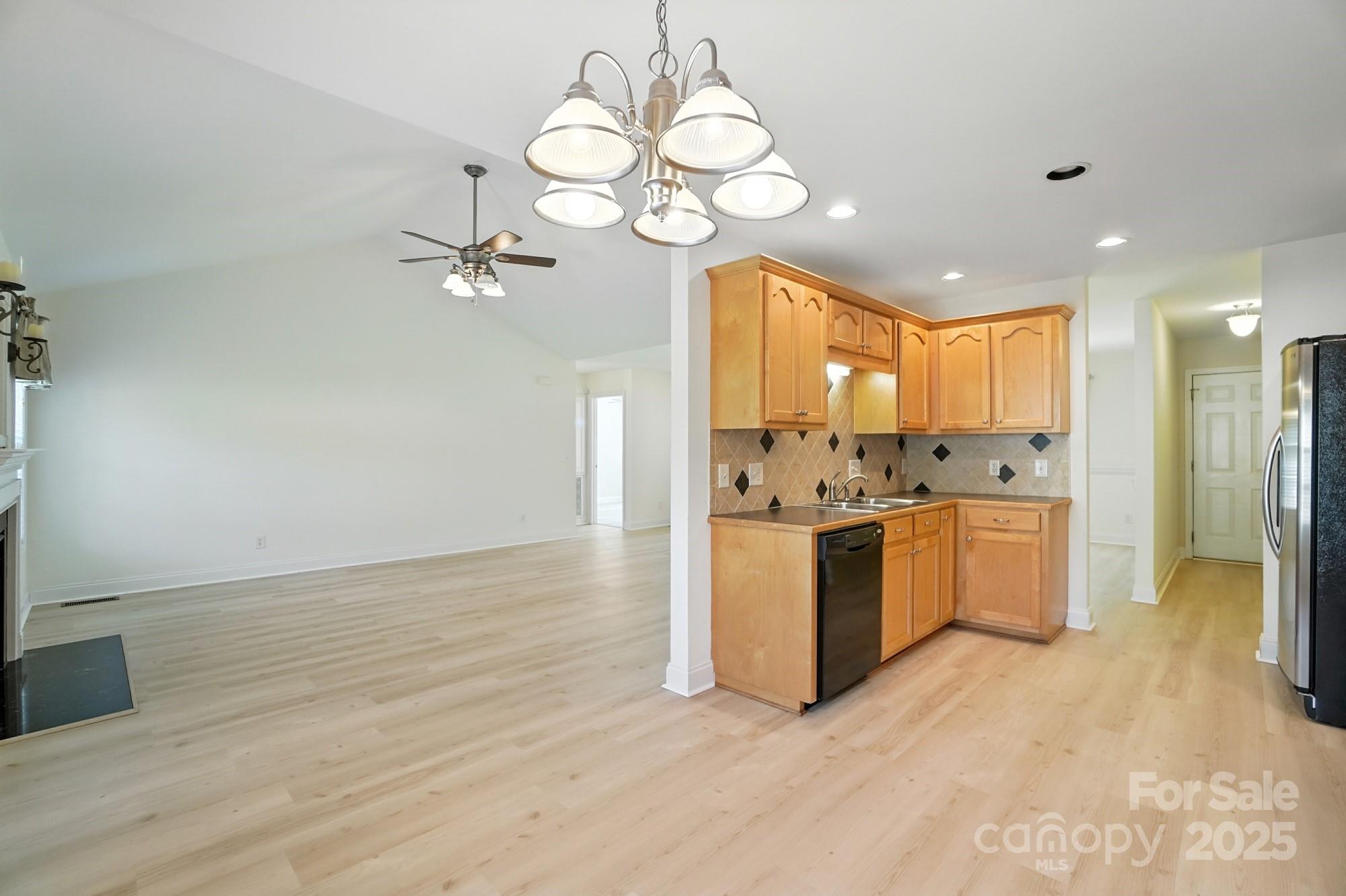 708 Redah Avenue Locust, NC 28097 - Photo 11 of 48 a open kitchen with a refrigerator a stove top oven a sink and dishwasher with wooden floor