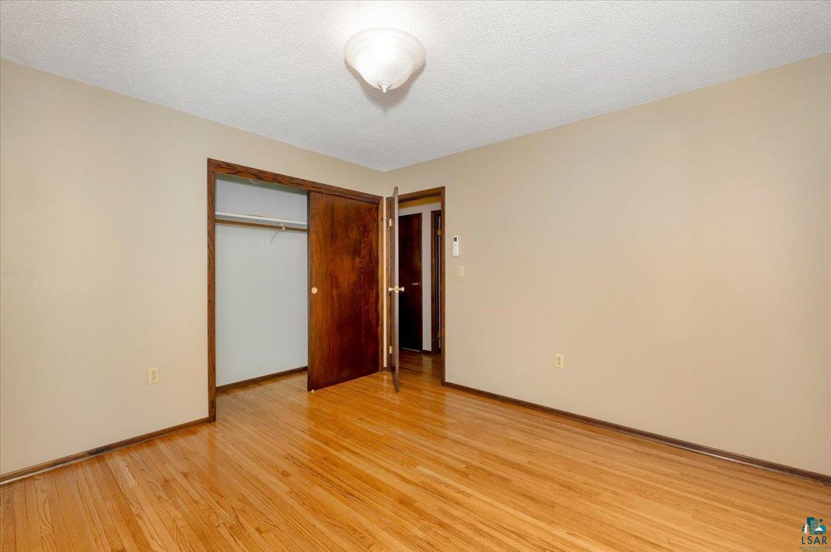 5219 West Arrowhead Road Hermantown, MN 55811 - Photo 15 of 35 Unfurnished bedroom with light hardwood / wood-style floors, a textured ceiling, and a closet