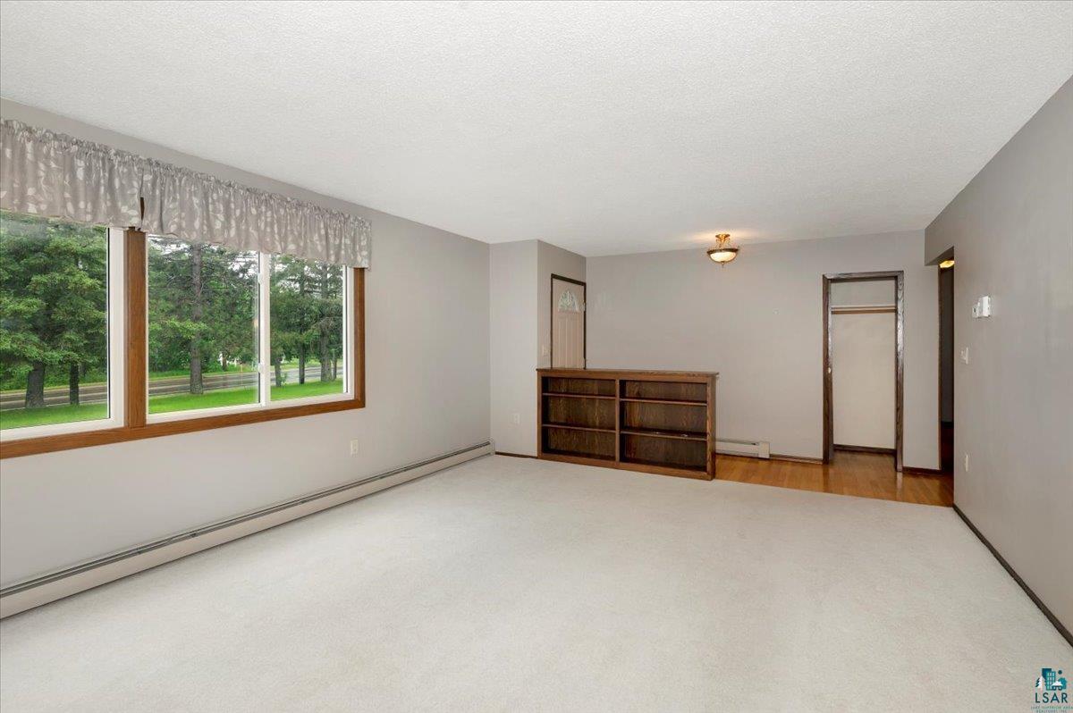 5219 West Arrowhead Road Hermantown, MN 55811 - Photo 2 of 35 Unfurnished bedroom featuring baseboard heating, carpet, and a closet