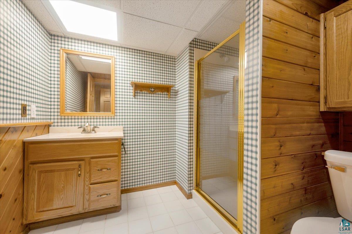 5219 West Arrowhead Road Hermantown, MN 55811 - Photo 22 of 35 Bathroom with vanity with extensive cabinet space, toilet, a drop ceiling, tile flooring, and an enclosed shower