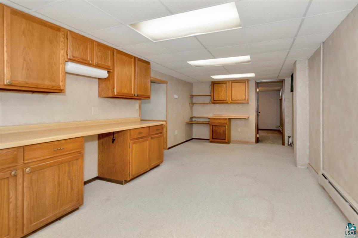 5219 West Arrowhead Road Hermantown, MN 55811 - Photo 23 of 35 Kitchen featuring light colored carpet, built in desk, a baseboard heating unit, and a drop ceiling