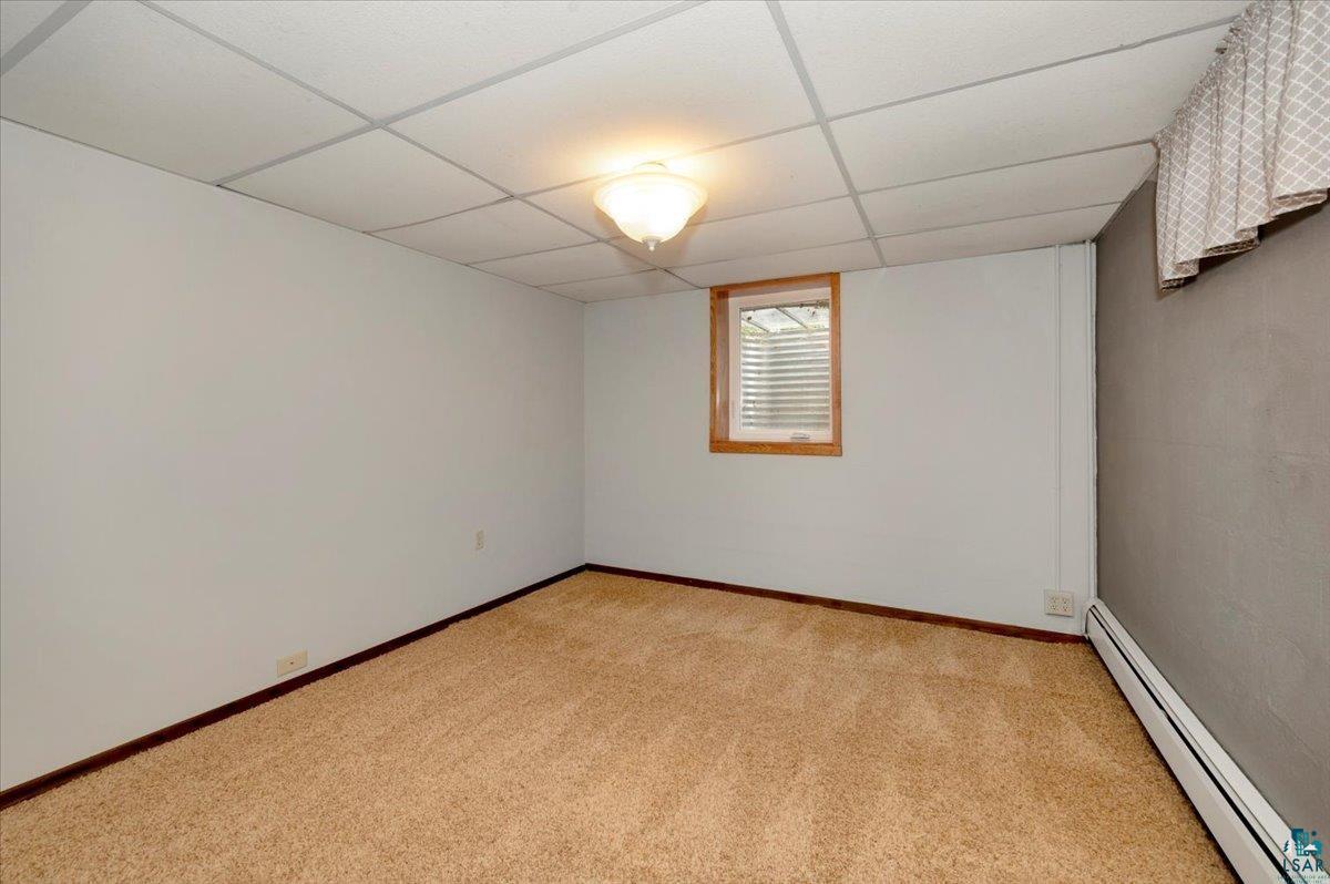 5219 West Arrowhead Road Hermantown, MN 55811 - Photo 25 of 35 Carpeted empty room with a baseboard radiator and a paneled ceiling