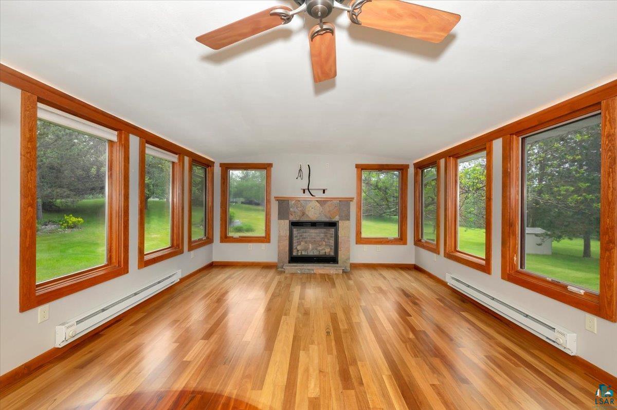 5219 West Arrowhead Road Hermantown, MN 55811 - Photo 6 of 35 Unfurnished living room featuring a baseboard heating unit, ceiling fan, and light wood-type flooring