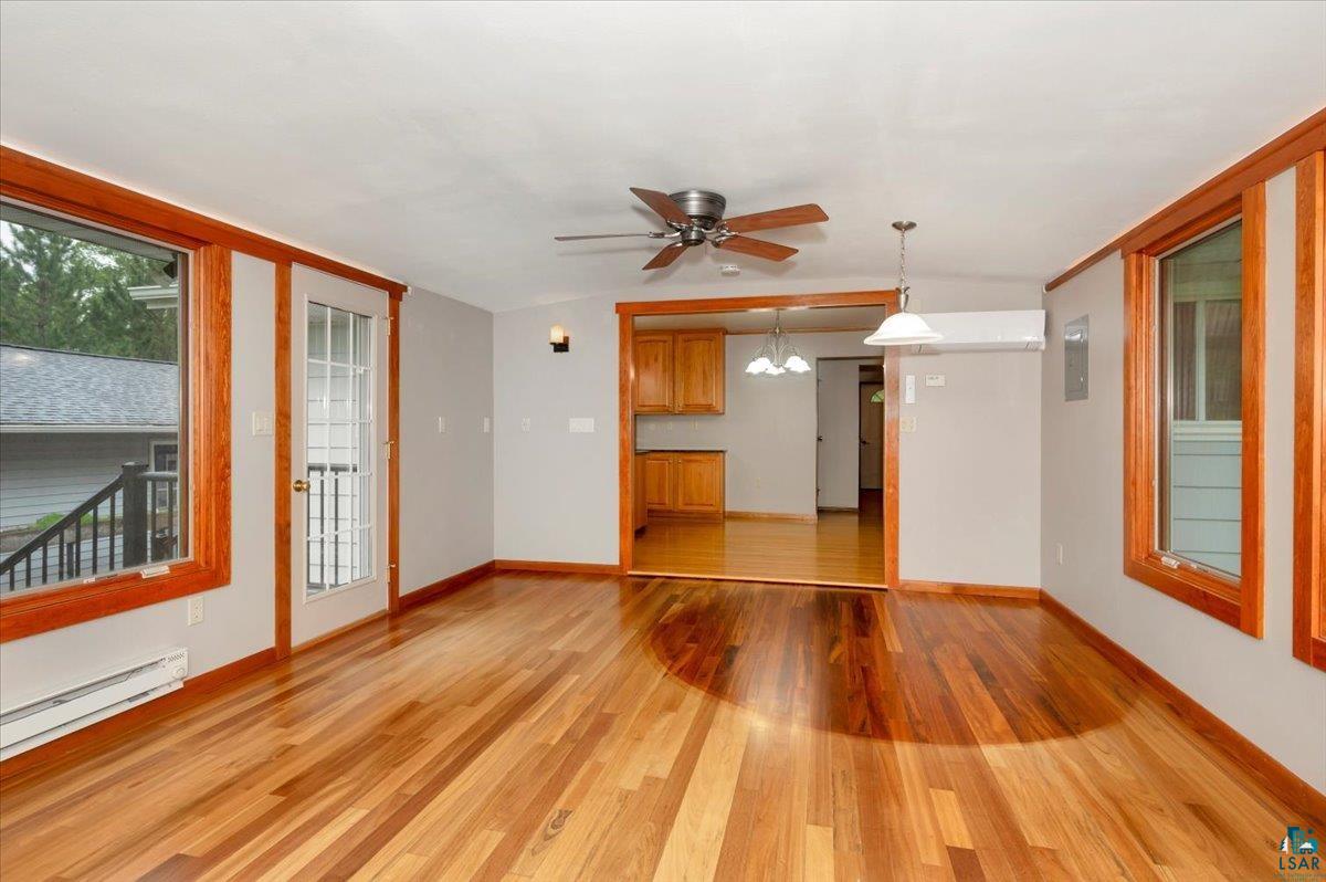 5219 West Arrowhead Road Hermantown, MN 55811 - Photo 7 of 35 Empty room featuring ceiling fan with notable chandelier, baseboard heating, and wood-type flooring