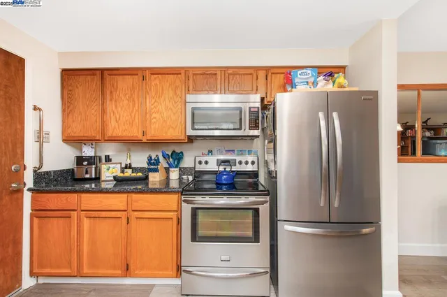 a kitchen with granite countertop a refrigerator stove top oven and sink