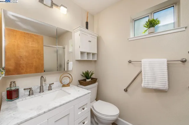 a bathroom with a granite countertop sink toilet and a mirror