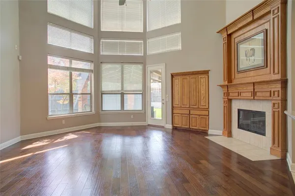 an empty room with wooden floor fireplace and windows