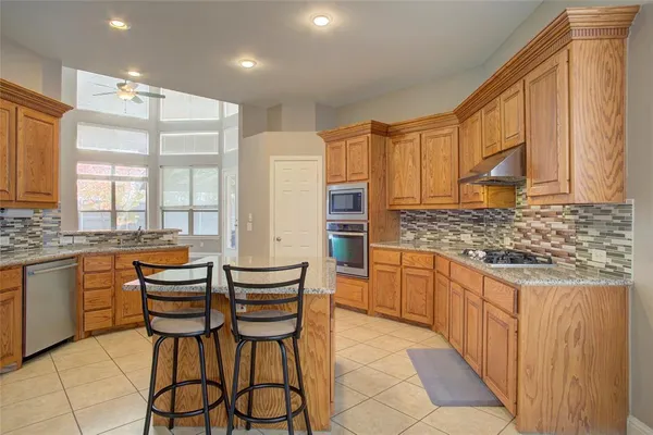 a kitchen with granite countertop wooden cabinets and stainless steel appliances