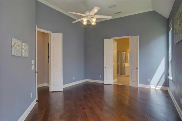 an empty room with wooden floor and a ceiling fan