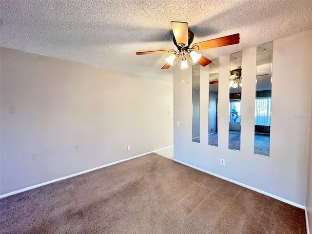 an empty room with chandelier fan and windows