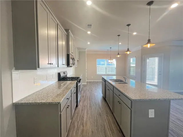 a kitchen with granite countertop a sink a counter top space stainless steel appliances and cabinets