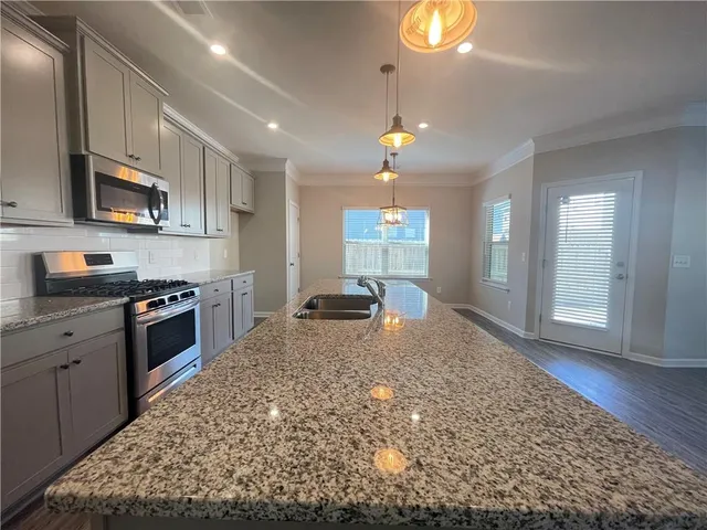 a kitchen with stainless steel appliances granite countertop a stove a sink and a microwave