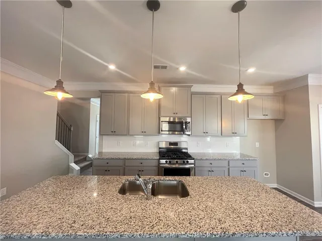 a kitchen with kitchen island a counter top space appliances and a sink