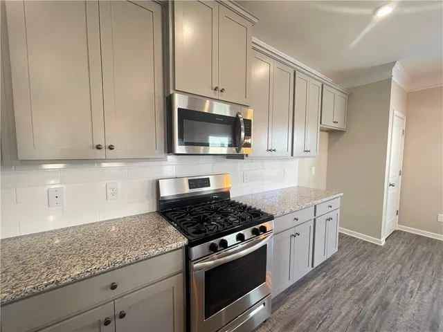 a kitchen with granite countertop stainless steel appliances white cabinets granite counter tops and a hard wood floors