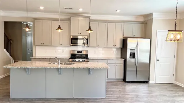 a kitchen with stainless steel appliances granite countertop a refrigerator a sink and a stove