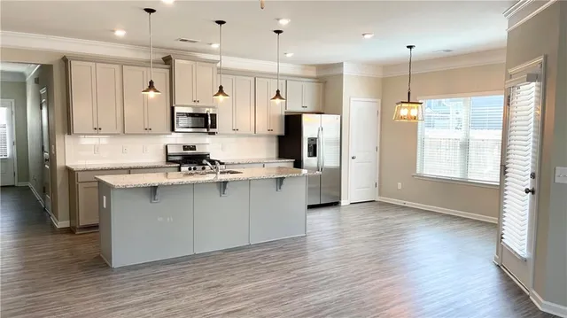 a kitchen with stainless steel appliances granite countertop a refrigerator a sink dishwasher a stove and white cabinets with wooden floor