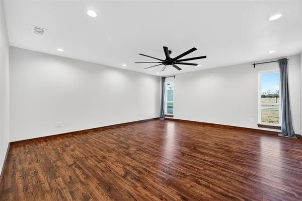 a view of a room with wooden floor and a ceiling fan